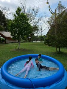 three children playing in a pool in a backyard at Kaitoon's River House in Ratchaburi