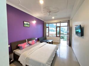 a bedroom with purple walls and a bed with pink pillows at Hotel Backpacers Mcleodganj in McLeod Ganj