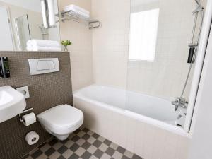 a bathroom with a toilet and a tub and a sink at HOTEL de la POSTE in Esch-sur-Alzette
