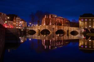 a bridge over a river in a city at night at Grand Hotel Valies in Roermond