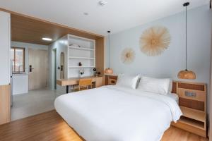 a bedroom with a large white bed and a kitchen at Modern Studio at Wing Samui in Bophut