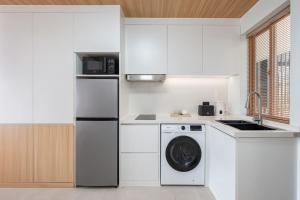 a white kitchen with a dishwasher and a washer at Modern Studio at Wing Samui in Bophut