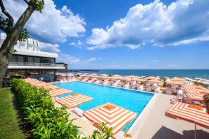 a swimming pool with umbrellas and chairs and the ocean at The Palace Hotel, Sunny Day in Saints Constantine and Helena