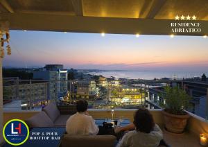 a group of people sitting on a balcony watching the sunset at Residence Adriatico in Gabicce Mare