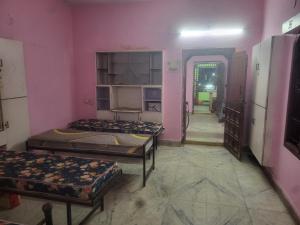 a room with three beds in a room with pink walls at Sagar Hotel For Family in Mācherla