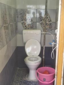 a bathroom with a toilet and a pink bucket at Sagar Hotel For Family in Mācherla