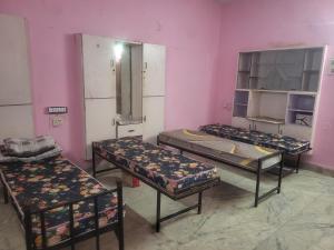 three beds in a room with pink walls at Sagar Hotel For Family in Mācherla