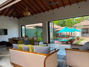 a living room with chairs and a patio with a pool at Eden Collection Thalpe in Talpe