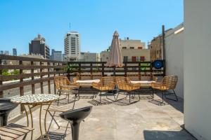a balcony with chairs and tables and an umbrella at Localz House- Trumpeldor Beach in Tel Aviv