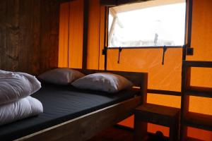a bed with two pillows in a room with a window at Lodge in de Ijsmolenhoeve in Ronse