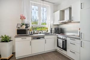 a white kitchen with white cabinets and appliances at Danma Ferienwohnung Apartment Eifel in Laubach