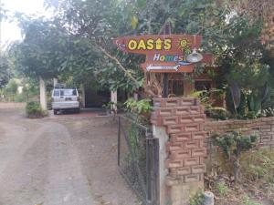 a sign for an oasis house with a fence at Oasis Homestay in Mendut