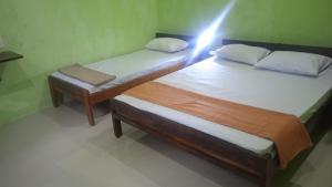 two beds in a room with a light on them at Oasis Homestay in Mendut