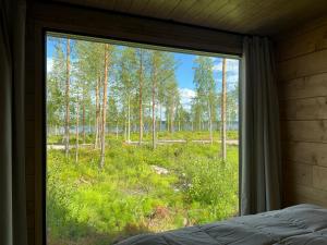 a bedroom window with a view of a forest at Tyven Resort in Sirkkakoski