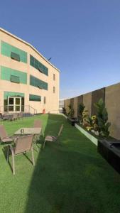 a building with chairs and a table in the grass at شقق اجنحة تارا in Khamis Mushayt