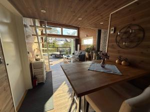 a kitchen with a wooden table and a living room at Skogsviken Guesthouse in Munkedal