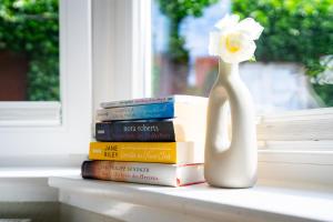 a stack of books and a vase with a flower on a window sill at Rosengarten in Kellenhusen