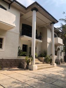 a house with columns and stairs in front of it at Centurion Aparthotel in Abuja