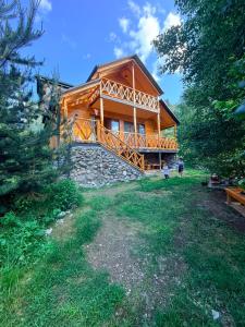 a log cabin with a large deck on a grass field at SymphonyA in Gorists'ikhe