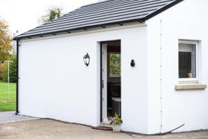a white garage with a black roof at Cherry Lodge by Escape Ordinary in Coleraine
