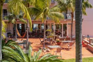 a patio with tables and chairs and palm trees at Florasol Residence Hotel - Dorisol hotels in Funchal