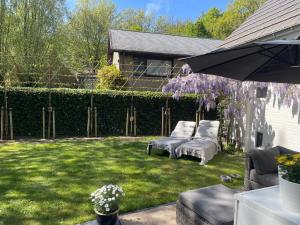 a group of white chairs in a yard with purple wisterias at TML Music Guesthouse in Aartselaar