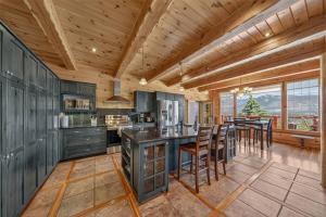 a kitchen with wooden ceilings and a large island with bar stools at Mountain View Log Home in Invermere in Invermere