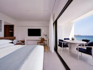 a bedroom with a bed and a table and a tv at Tinos Beach Hotel in Kionia