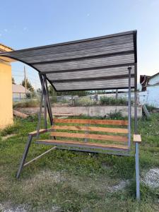 a wooden bench with a black roof on a field at Hanbiike in Karakol +6 photos