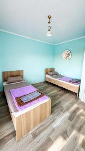 two beds in a room with blue walls and wooden floors at Familia Капчагай in Kapchagay