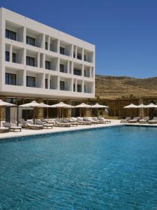 a hotel with a swimming pool with chairs and umbrellas at Tinos Beach Hotel in Kionia