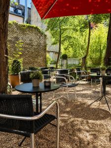a patio with tables and chairs and a red umbrella at HOTEL de la POSTE in Esch-sur-Alzette