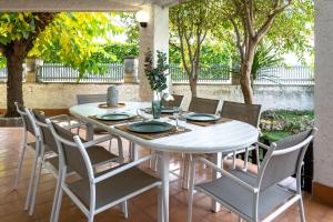 a white table and chairs in a patio with trees at Villa 30 m from the beach Cambrils in Cambrils