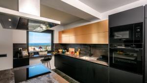 a kitchen with black cabinets and a large window at Luxury villa Mar with infinity pool in Rab in Palit