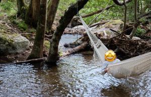 a person sitting in a hammock in a river at La GéoYourte in Saint-Vincent +1 photo
