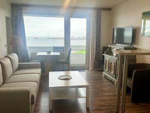 a living room with a couch and a tv and a window at Haus Nautic Whg 809 Seesicht in Cuxhaven