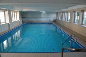 a large swimming pool with blue tile floors and windows at Haus Nautic Whg 809 Seesicht in Cuxhaven