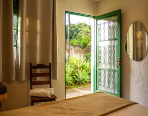 a bedroom with a door open to a garden at Pousada Refúgio Serrano in Serra Negra