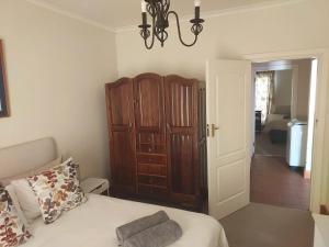 a bedroom with a bed and a wooden cabinet at Nguni Cottage in Graaff-Reinet +2 photos