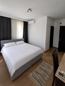 a bedroom with a large white bed and a table at Berane Rooms in Berane