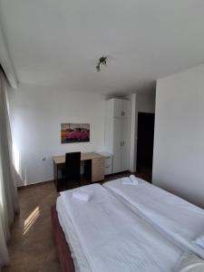 a bedroom with a white bed and a desk and a table at Berane Rooms in Berane