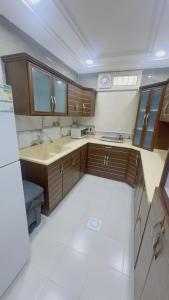 a large kitchen with wooden cabinets and a white floor at شقق اجنحة تارا in Khamis Mushayt