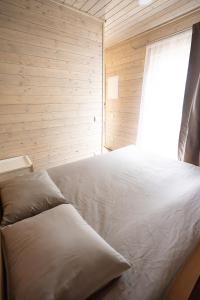 a bedroom with a white bed with a window at Mērsraga namiņš in Mērsrags