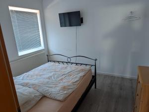 a bed in a room with a tv on the wall at IBB Ferien- Monteurwohnung 3 Schlafzimmer 3 Betten in Ibbenbüren