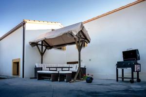 a patio with a umbrella and chairs and a grill at El Rincón del Silencio in Entrala