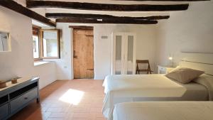 a bedroom with two beds and a table and a door at Ca La Remei i Can Benet in Els Hostalets d'en Bas