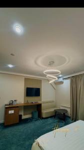 a hotel room with a bed and a desk and a television at Radamis in Almaty