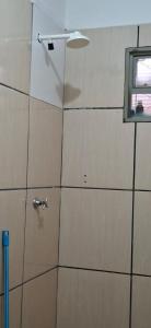 a tiled bathroom with a shower with a window at Home Comfort in Poconé