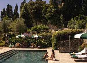 two women sitting next to a swimming pool at Torre a Cona Wine Estate in Florence