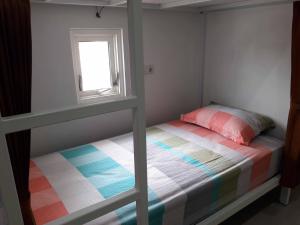 a small bedroom with a bunk bed with a window at Huize Jon Hostel in Malang